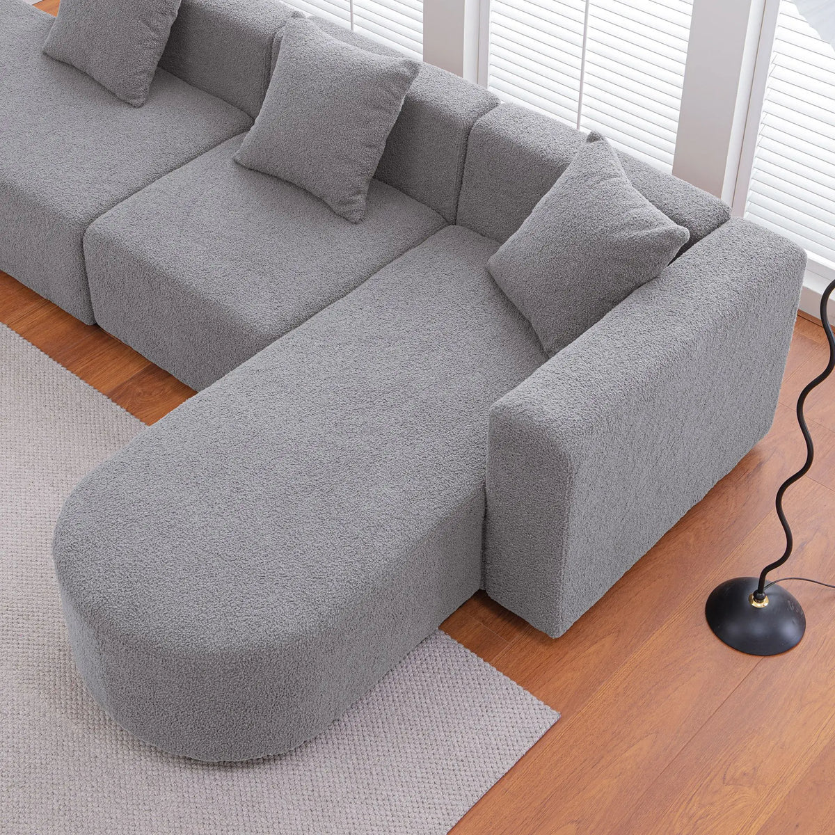 Grey bouclé L-shaped sectional sofa with curved round seat, facing right