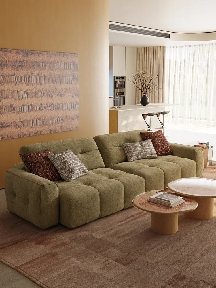 Olive linen CloudNest sofa beneath abstract artwork with honey-toned walls and round stone tables. Digital interior design study.