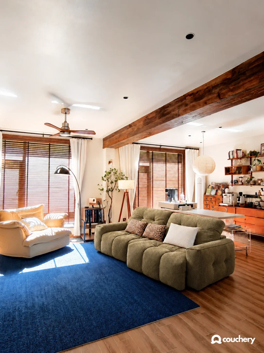 Olive textured weave CloudNest in a warm eclectic living room; timber, collected objects and a generous blue rug. Edited design study.