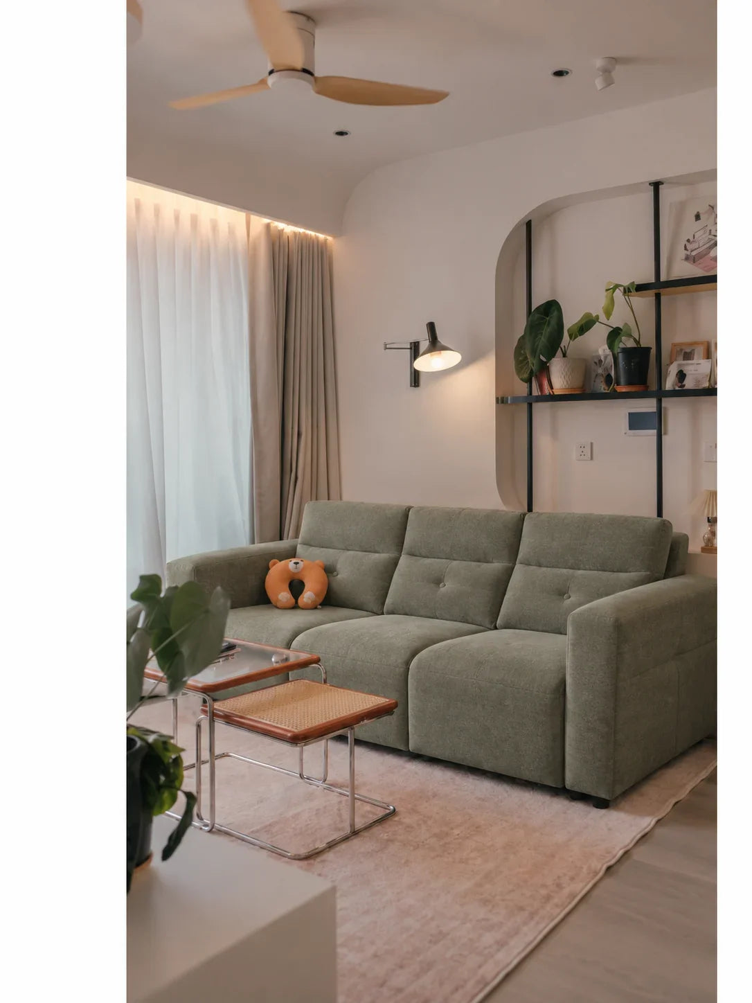 Sage-green Serenity recliner sofa in a real compact apartment living room with a curved shelf niche. Edited design study.
