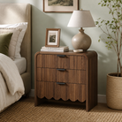 Fluted walnut nightstand with scalloped wave base in a bedroom
