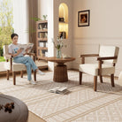 Two mid-century solid wood armchairs with beige cushions in a living room