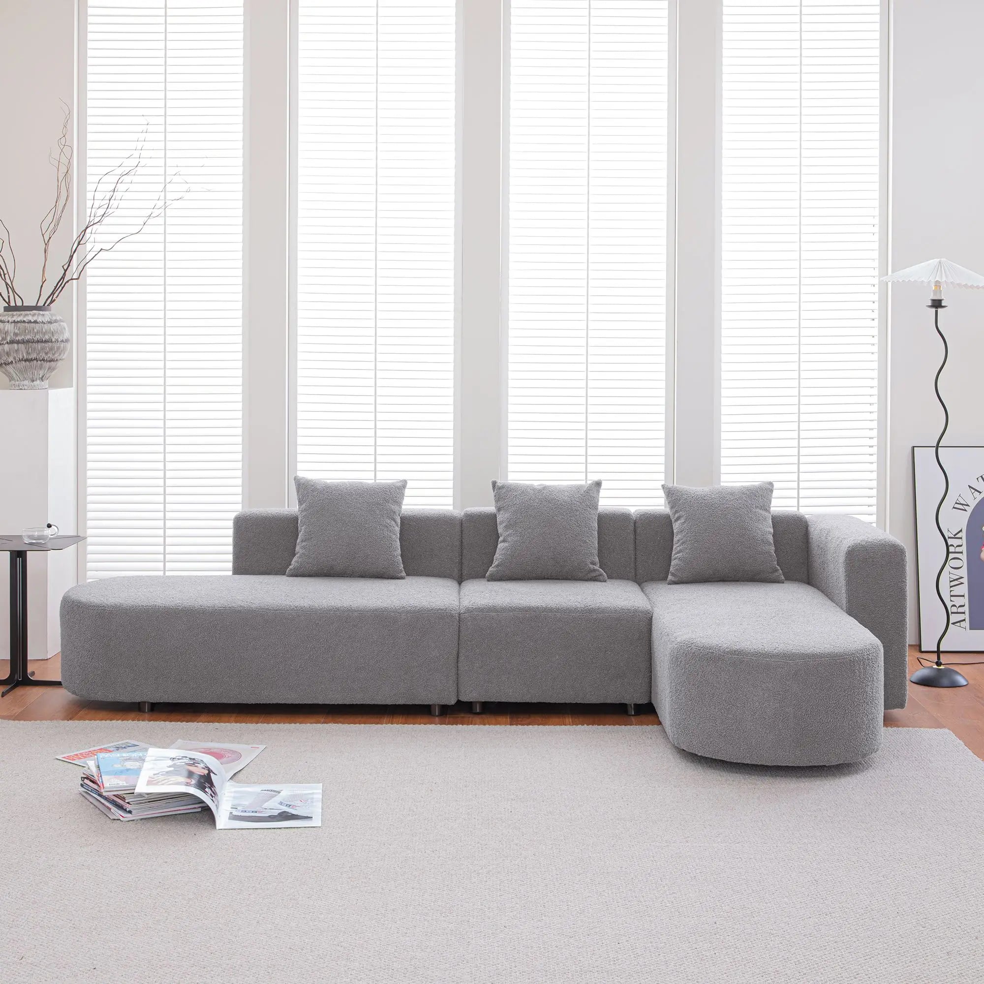 Grey bouclé L-shaped sectional sofa with curved round seat, facing right