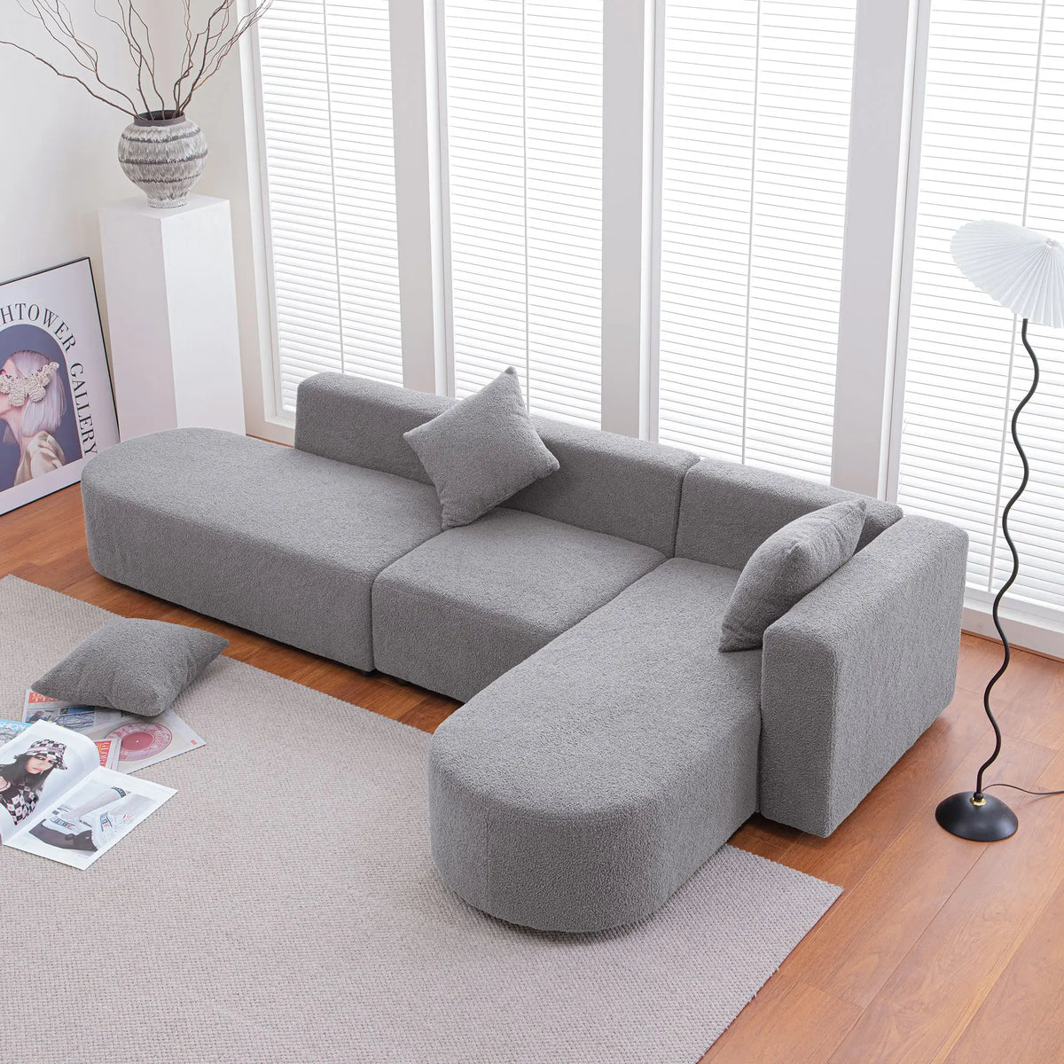 Grey bouclé L-shaped sectional sofa with curved round seat, facing right