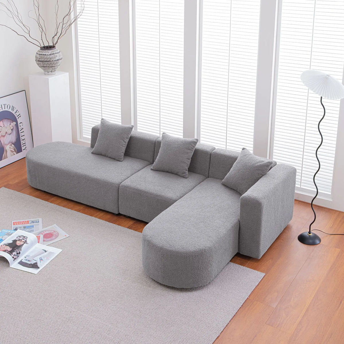 Grey bouclé L-shaped sectional sofa with curved round seat, facing right