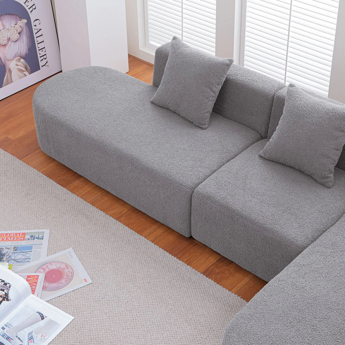 Grey bouclé L-shaped sectional sofa with curved round seat, facing right